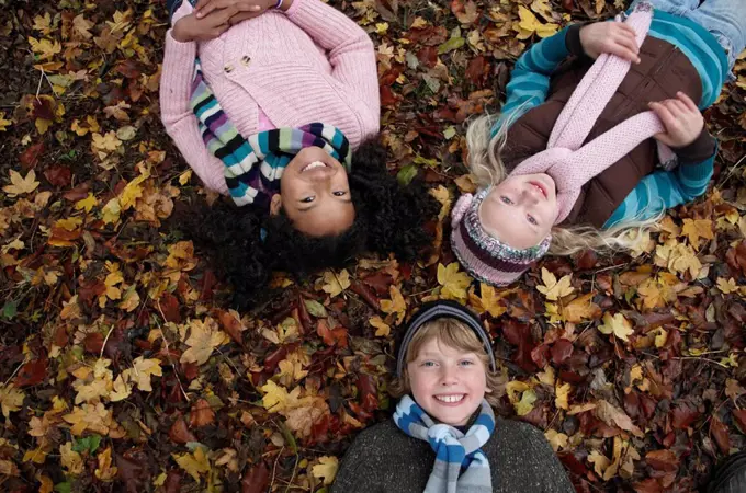 Three friends lying on autumn leaves