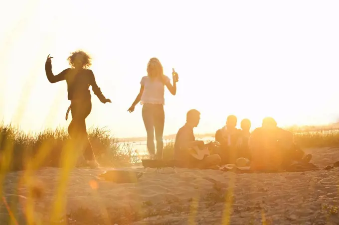 Six adult friends partying at sunset on Bournemouth beach, Dorset, UK