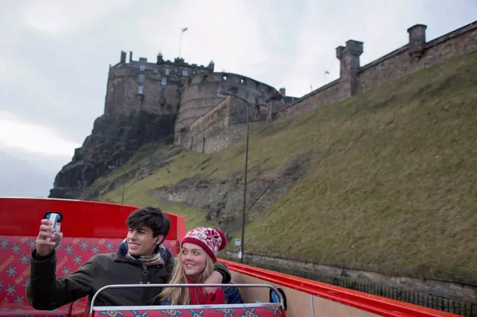 A young couple on an open-top bus tour of Edinburgh Scotland