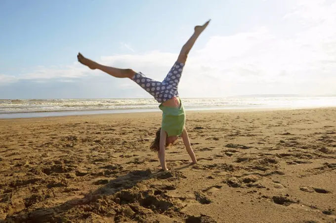 Girl doing handstand on beach, Camber Sands, Kent, UK