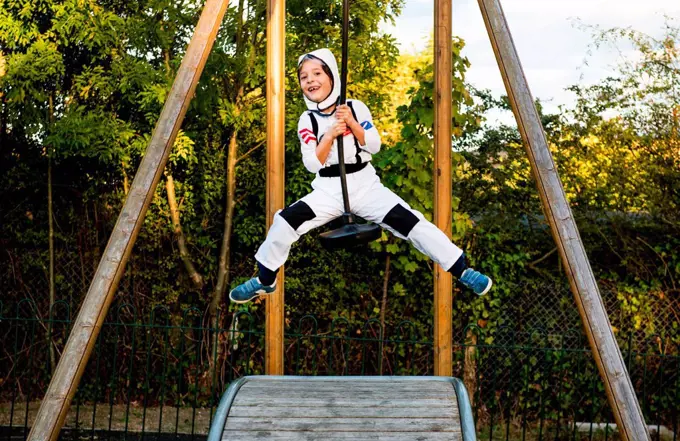 Portrait of boy in astronaut costume riding on playground zip wire