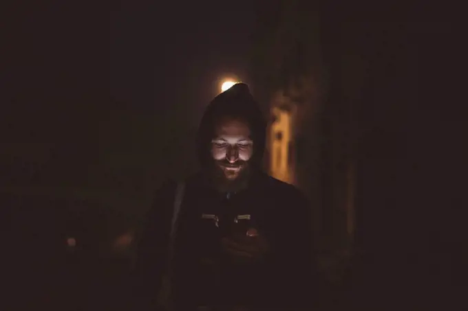 Man looking down at smartphone at night, Venice, Italy