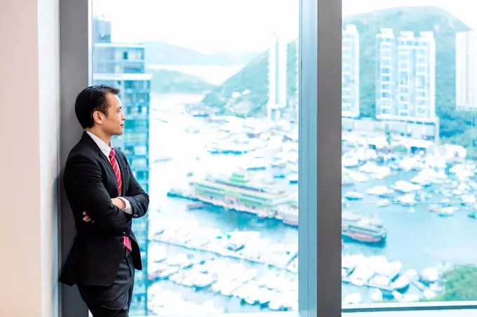 Businessman looking out of window at view of harbour