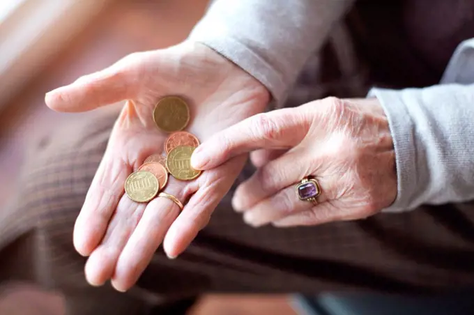 Senior woman counting coins in hand, close-up