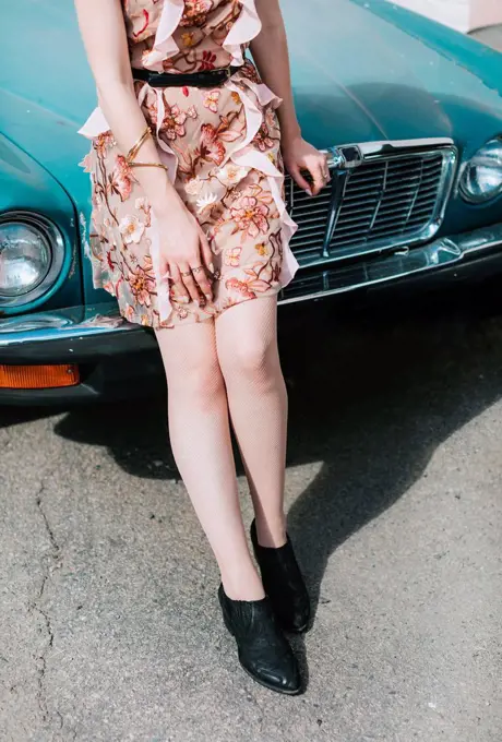 Cropped view of woman leaning against vintage car
