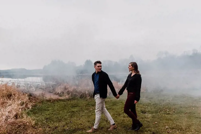 Young couple holding hands walking on misty grassland, Ottawa, Canada