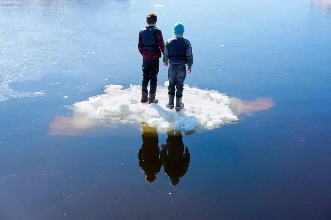 Two boys standing on ice, on lake, rear view