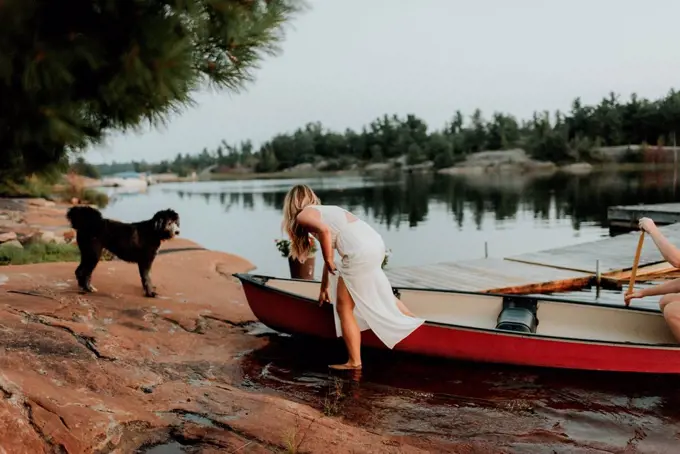 Couple and pet dog getting off boat, Algonquin Park, Canada