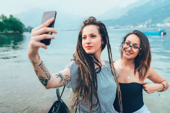 Girlfriends taking selfie by sea