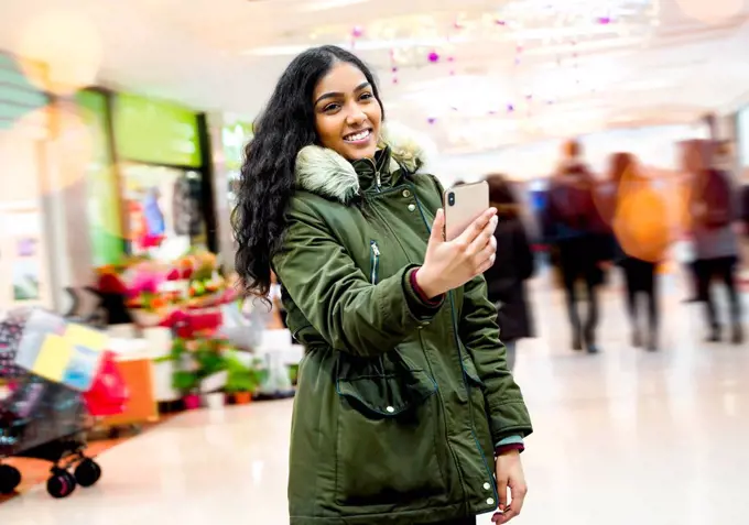 Young woman taking selfie in shopping mall