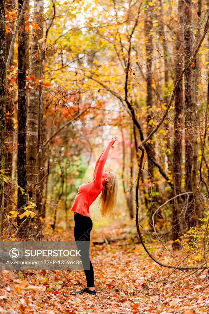 Blond woman in fitness clothing in a forest in the fall.