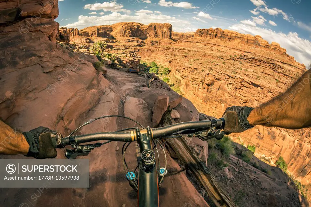 A point of view perspective of a mountain biker riding a trail in a rugged desert area.