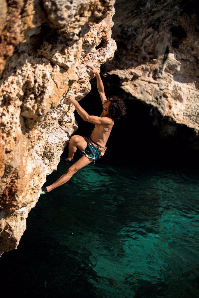 Man doing psicobloc in Mallorca, Spain. Psicobloc is a rock climbing discipline where the climber climbs without rope and other safety gear on selloff...