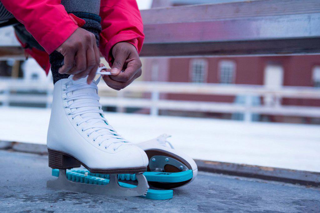 Low section photograph of African American woman putting on ice skate