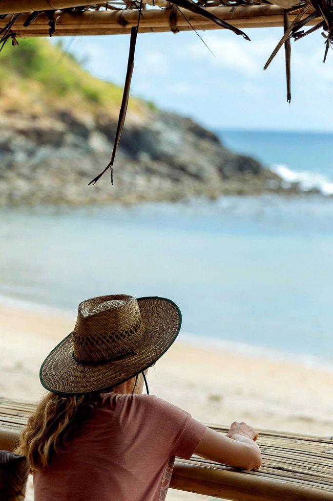 Rearâ€ view ofâ€ femaleâ€ tourist in straw hat looking at sea from beach, Bali, Indonesia