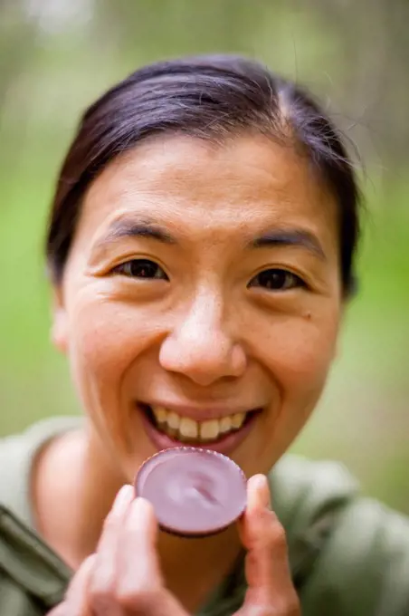 A Japanese American woman holds a Justin's Dark Chocolate Peanut Butter Cup.