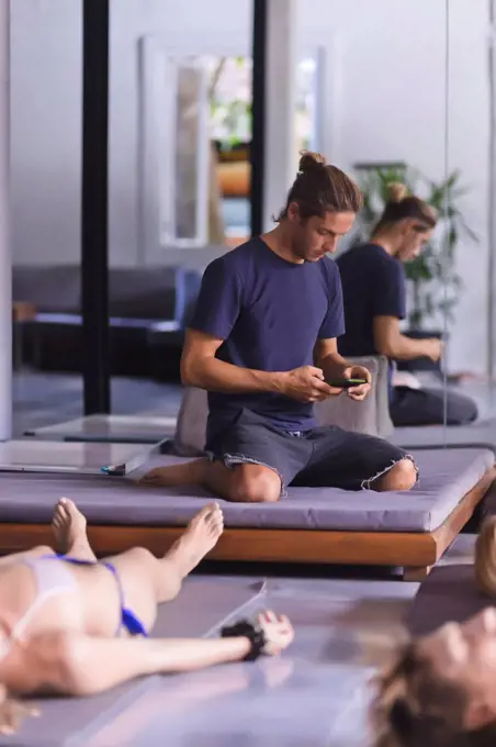 Young man with phone in yoga class