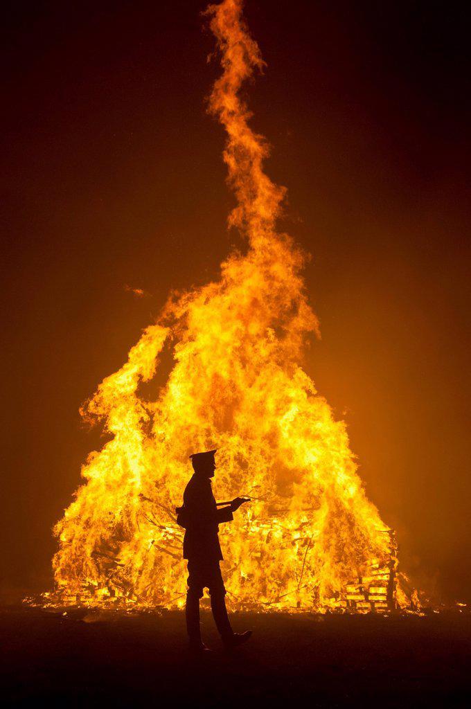 Silhouette Of Man In Military Unifrom In Front Of Large Bonfire At Barcombe Bonfire Night, Barcombe, East Sussex, Uk