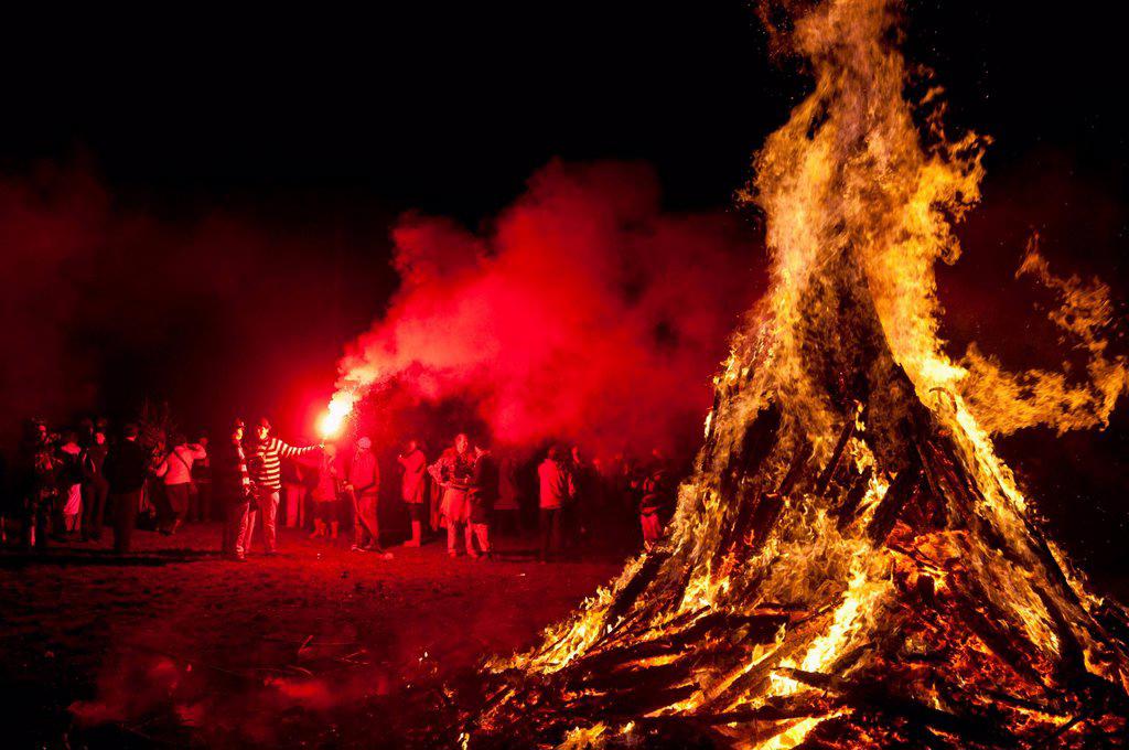 Man with red flare beside large bonfire at Battle Bonfire Night; East Sussex, England, UK