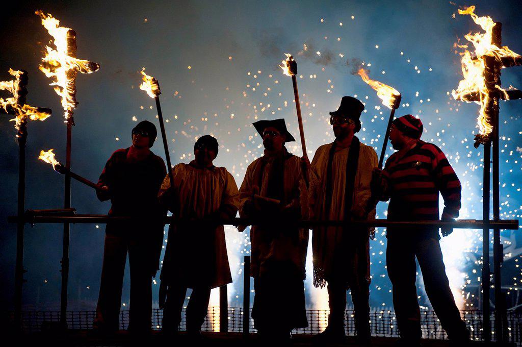 People dressed as clergy on stand with fireworks behind them at Newick Bonfire Night; East Sussex, England, UK