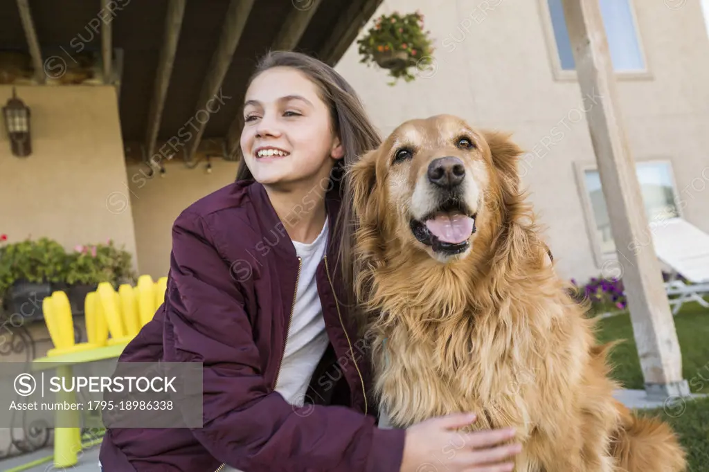 Girl (12-13) with Golden Retriever in front of house