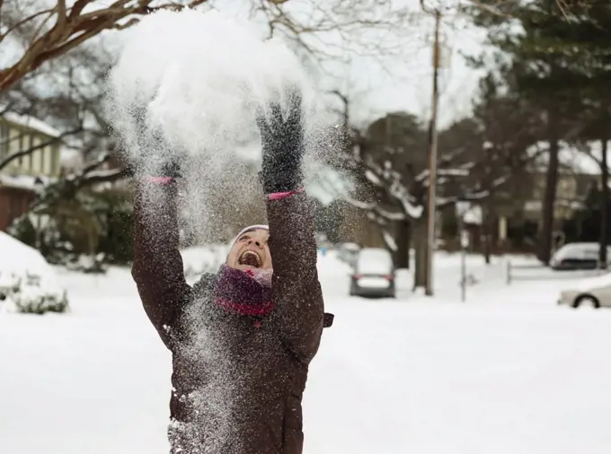 Teenage girl throwing powdered snow mid air
