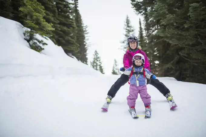 Little girl (2-3) learning skiing with mother