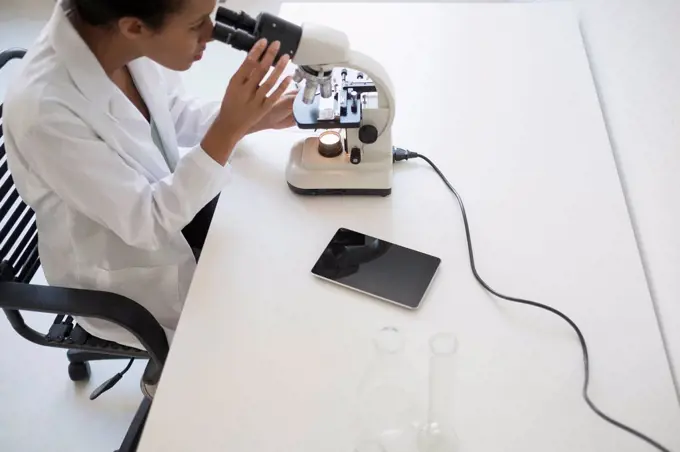 Woman scientist looking through microscope