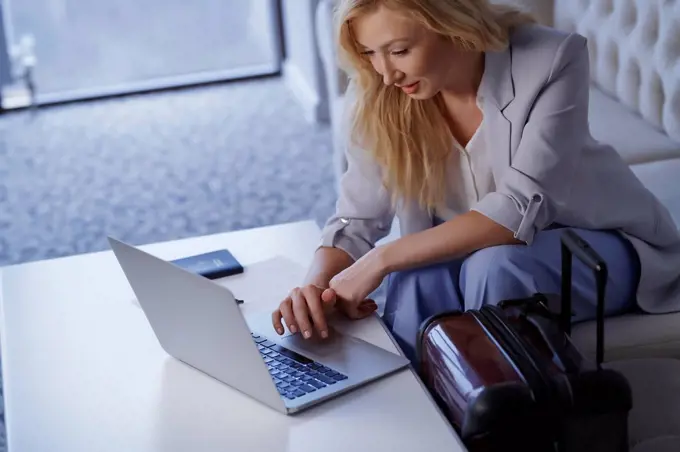 Businesswoman working on laptop in airport lounge