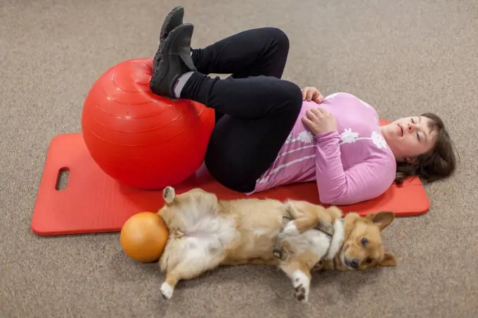 Girl with Down Syndrome working out on a yoga mat with her dog