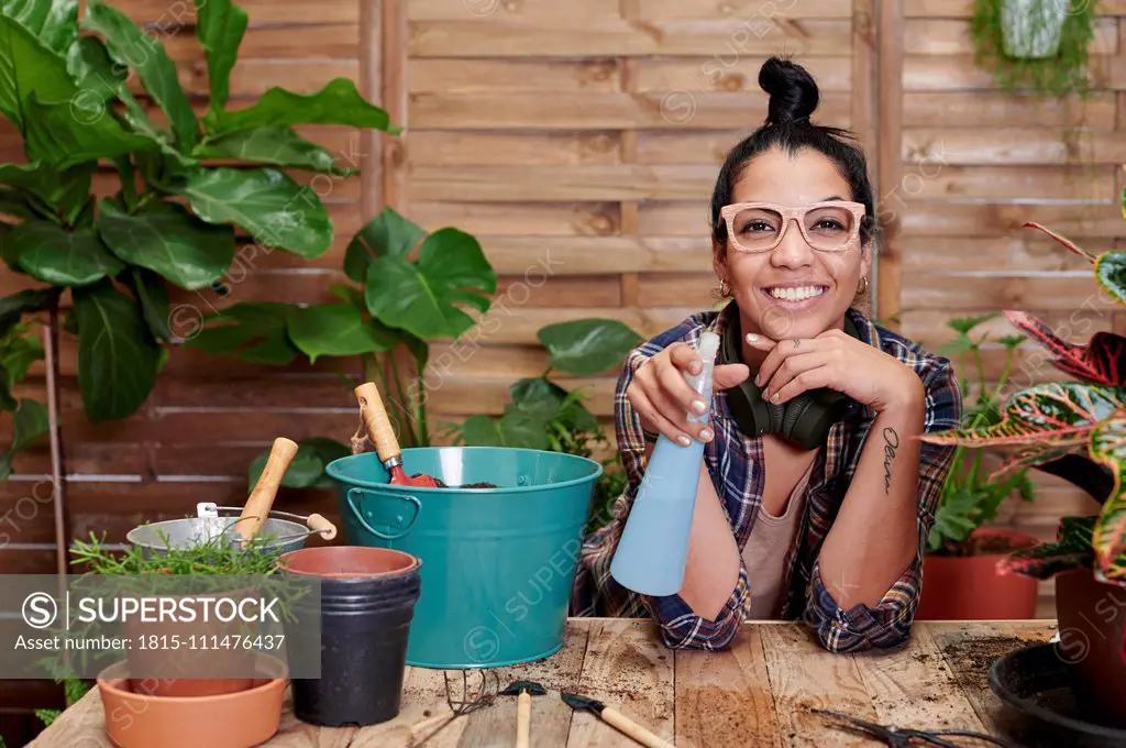 Portrait of a smiling young woman gardening on her terrace