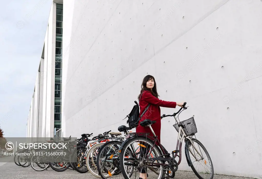 Businesswoman taking bicycle in the background of modern building