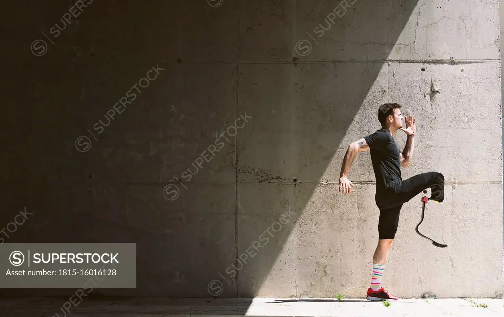 Disabled athlete with leg prosthesis practising at a concrete wall