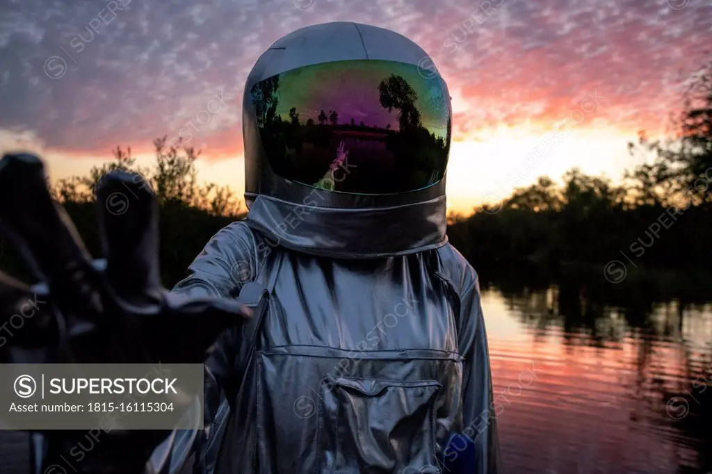 Portrait of spacewoman with raising arm at sunset
