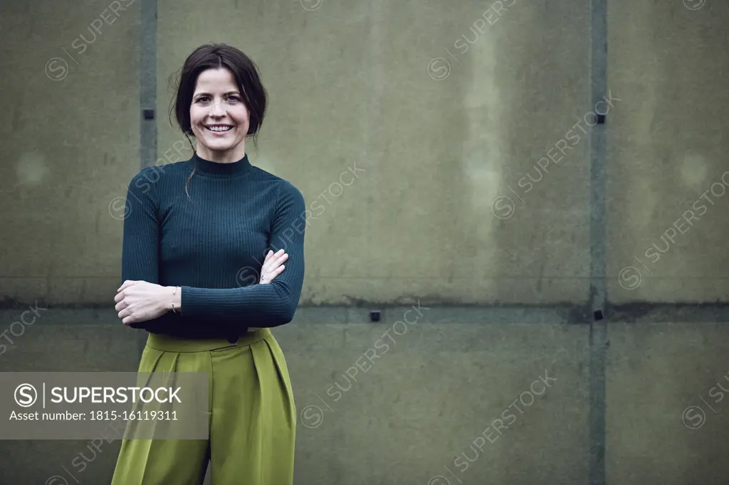 Portrait of smiling businesswoman standing at a green wall