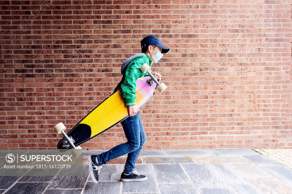 acceptable holy policy Boy wearing protective mask and walking with longboard in front of a brick  wall - SuperStock