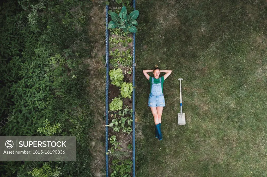 Aerial view of woman lying by raised bed on land in yard