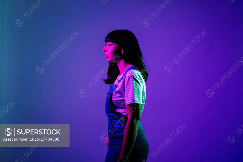 Young woman standing against colored background