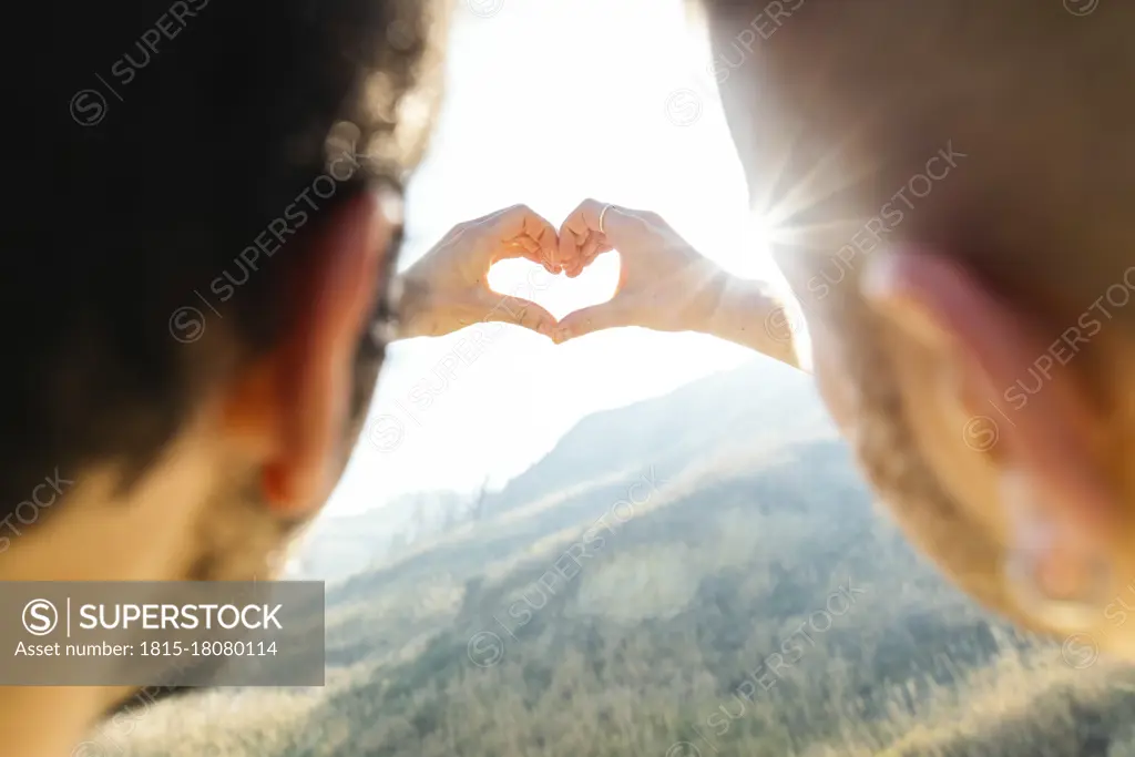 Gay couple doing heart shape with hands at beach