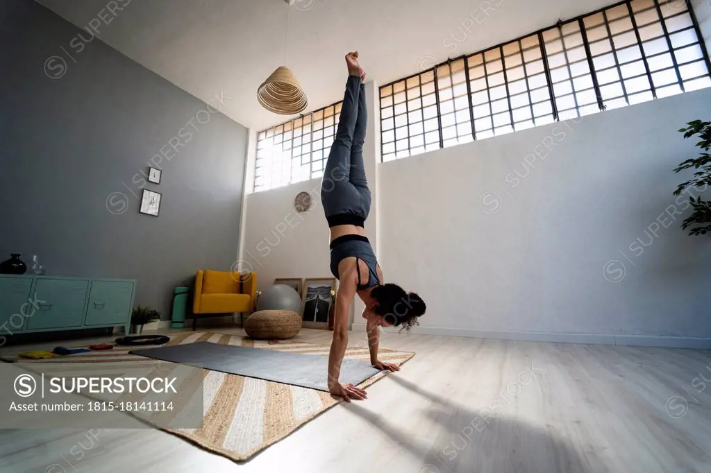 Young woman balancing on hands in living room