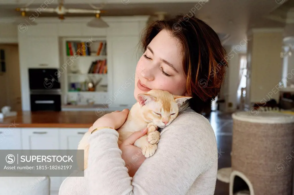 Beautiful woman embracing cat at home