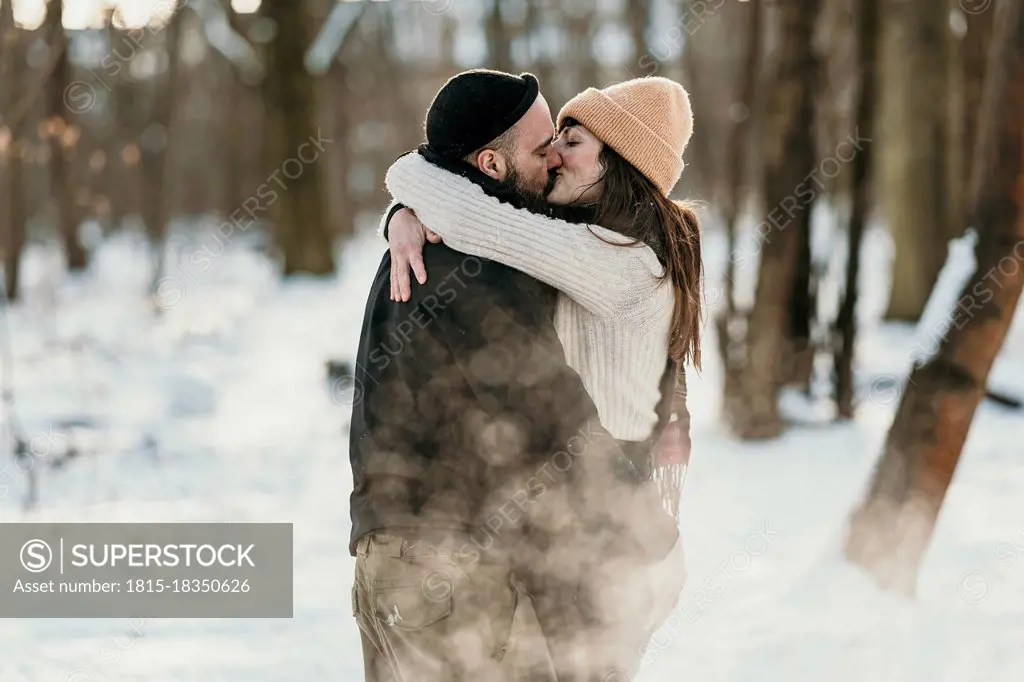 Mid adult boyfriend and girlfriend kissing in forest