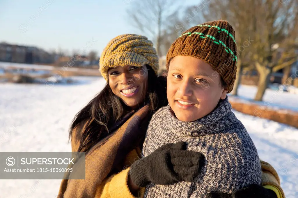 Smiling mother and son wearing knit hat standing together during winter