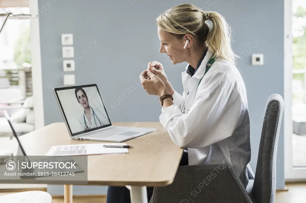 Female professional gesturing while discussing with colleague through video call on laptop at office