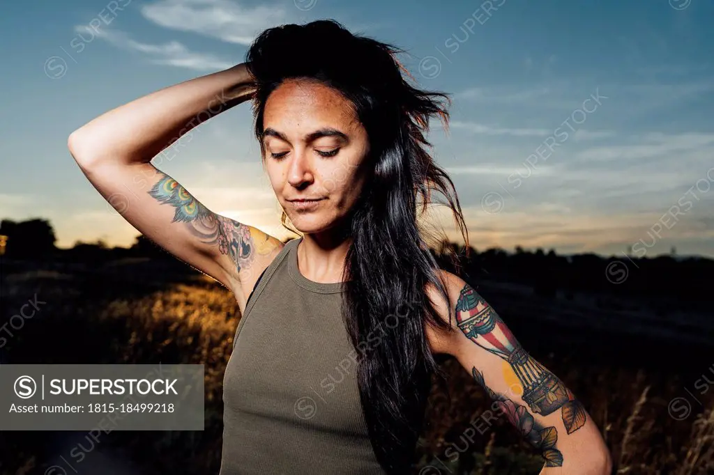 Mid adult woman with hand in hair during sunset