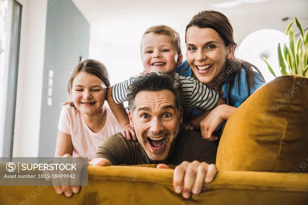 Man playing with family on sofa at home