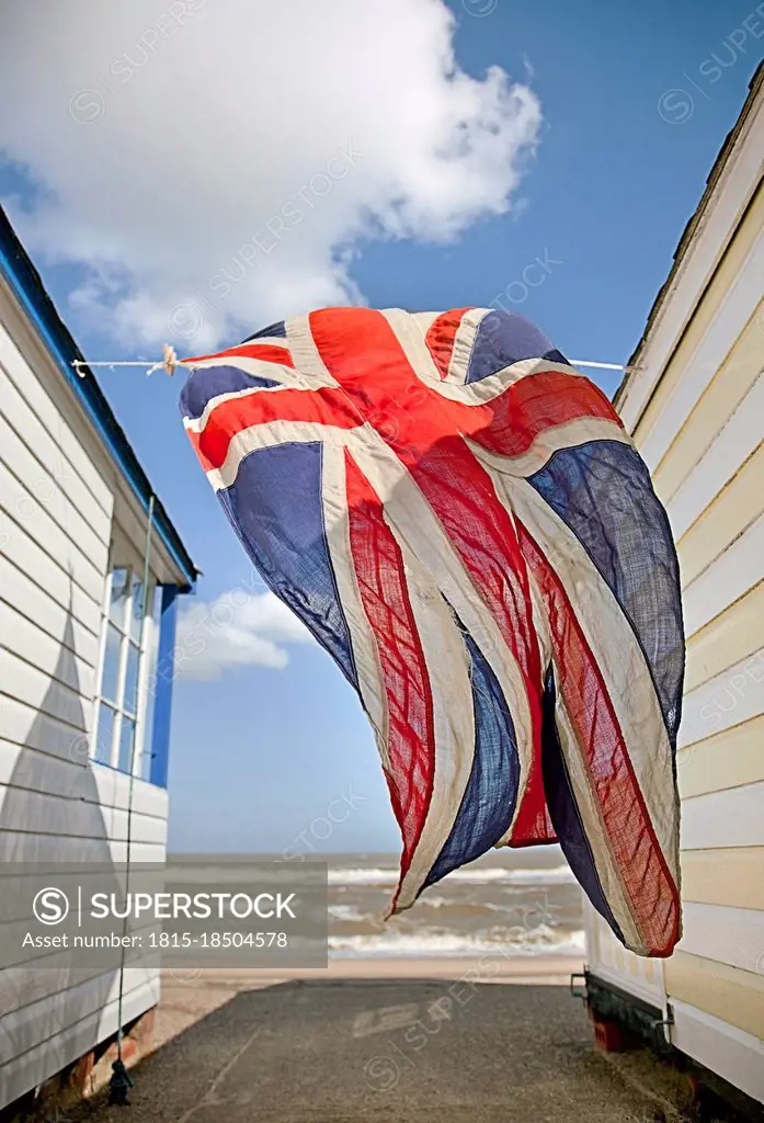 British Flag hanging between beach huts during sunny day