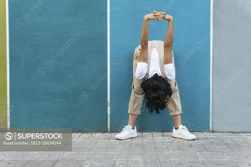 Flexible young woman doing stretching exercise on footpath