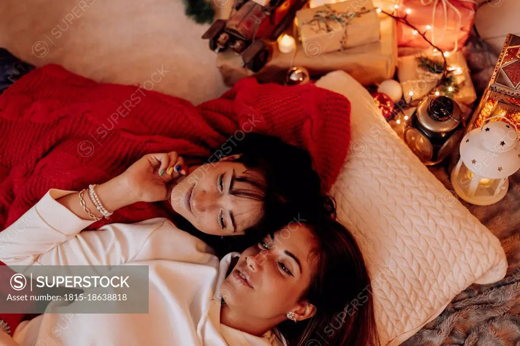 Female friends resting by Christmas decoration at home