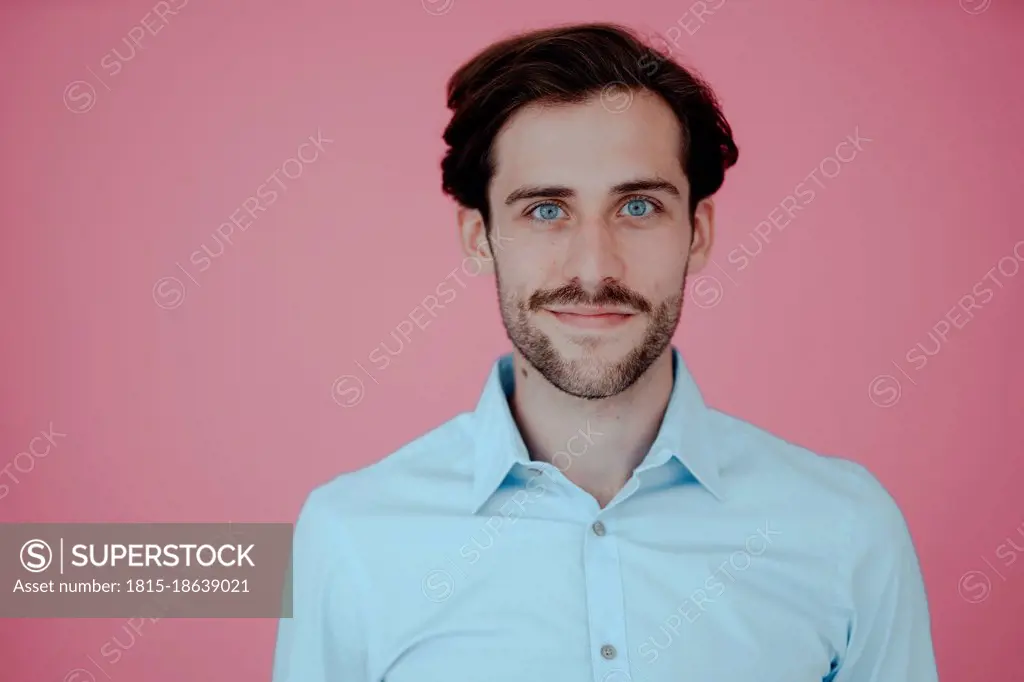 Smiling businessman against pink background